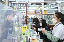 Giải thích cho khách về thuốc Molnupiravir điều trị COVID-19. (Ảnh: Minh Quyết/TTXVN)