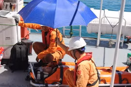 Các nhân viên cứu hộ của tàu SAR 27-01 chuẩn bị đưa nạn nhân từ tàu lên bờ. (Ảnh: Phan Sáu/TTXVN)