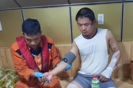 Nhân viên của Trung tâm Phối hợp tìm kiếm, cứu nạn hàng hải Việt Nam kiểm tra sức khỏe nạn nhân (áo trắng bên phải) trên tàu SAR 27-01. (Ảnh: Phan Sáu/TTXVN)