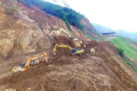 Các đơn vị thi công đang khẩn trương san gạt đất đá sạt lở sớm thông tuyến đường lên huyện Mường Lát. (Ảnh: Trịnh Duy Hưng/TTXVN)