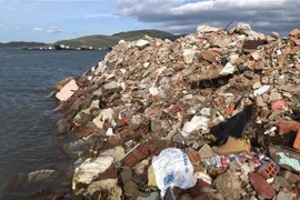 Hàng ngàn khối đất đá, xà bần đổ xuống lấp đầm Thị Nại. (Ảnh: Nguyên Linh/TTXVN)