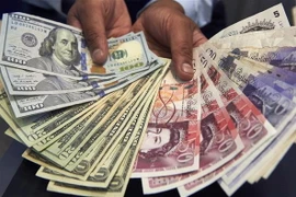 Đồng USD (trái) và đồng bảng Anh (phải) tại quầy giao dịch tiền tệ ở London, Anh. (Nguồn: AFP/TTXVN)