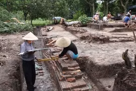 Các nhà khảo cổ đo diện tích nền gạch cổ tại một điểm khai quật tại khu di tích Gò Tháp. (Ảnh: TTXVN)