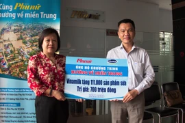 Ông Nguyễn Trung, Chủ tịch Công đoàn Công ty Vinamilk đại diện tập thể người lao động của công ty trao bảng tượng trưng 111.000 sản phẩm dinh dưỡng ủng hộ đồng bào miền Trung. (Nguồn: Vietnam+)