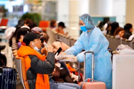 Nhân viên của Cảng hàng không phục vụ suất ăn và nước uống miễn phí đối với những hành khách đang chờ làm thủ tục y tế và đi đến điểm cách ly theo đúng quy định. (Ảnh: CTV/Vietnam+)
