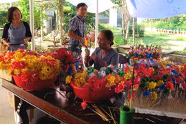 Nhiều du khách đến với làng nghề để tìm hiểu và trải nghiệm các công đoạn làm hoa. (Ảnh: Tường Vi/TTXVN)