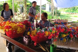 Nhiều du khách đến với làng nghề để tìm hiểu và trải nghiệm các công đoạn làm hoa. (Ảnh: Tường Vi/TTXVN)