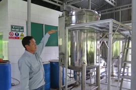 Anh Dương Văn Toản, Phó Giám đốc Khu du lịch Cánh đồng bất tận giới thiệu về hệ thống chưng cất tinh dầu - nơi du khách được trải nghiệm trồng và chế biến tinh dầu tràm. (Ảnh: Minh Hưng/TTXVN)