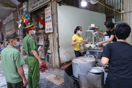 Công an phường Hàng Mã nhắc nhở nhân dân thực hiện nghiêm việc giãn cách, đeo khẩu trang để phòng, chống dịch COVID-19. (Ảnh: Doãn Tấn/TTXVN)