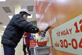 Người nghèo, người có hoàn cảnh khó khăn nhận gạo miễn phí từ cây ATM gạo đặt tại phường Phúc Diễn, quận Bắc Từ Liêm, Hà Nội. (Ảnh: TTXVN)