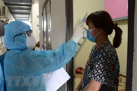 Kiểm tra thân nhiệt cho người dân. (Nguồn: TTXVN)