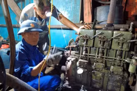 Cán bộ kỹ thuật Âu tàu đảo Sinh Tồn giúp ngư dân sửa chữa máy phát điện của tàu cá QNg 90431 TS. Ảnh: TTXVN phát