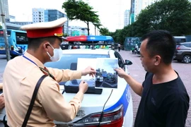 Lực lượng CSGT cho tài xế xe khách xem lại hình ảnh vi phạm để làm căn cứ xử phạt theo quy định pháp luật. (Ảnh: Phạm Kiên/TTXVN)