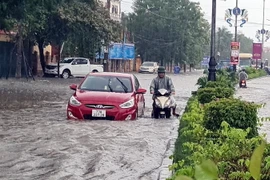 Nhiều phương tiện giao thông rất khó khăn khi lưu thông qua các tuyến đường ngập nước tại thành phố Đồng Hới, tỉnh Quảng Bình. (Ảnh: Tá Chuyên/TTXVN)