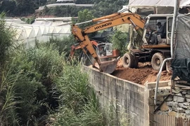 Lực lượng chức năng sử dụng phương tiện cơ giới để cưỡng chế công trình vi phạm xây dựng kiên cố. (Ảnh: TTXVN phát)