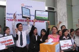 Nhân viên DongA Bank và khách hàng cùng quyên góp ủng hộ ngư dân bám biển. (Ảnh: Hà Huy Hiệp/Vietnam+)