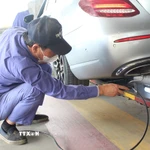 Nhân viên đăng kiểm thực hiện thao tác trong quy trình kiểm định khí thải. (Ảnh: Nguyễn Thắng/TTXVN)