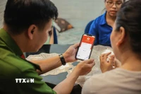Tổ chuyển đổi số cộng đồng hướng dẫn người dân sử dụng ứng dụng định danh công dân trên môi trường kỹ thuật số (VNeID) có giá trị sử dụng thay thế các giấy tờ truyền thống. (Ảnh: Hoàng Hiếu/TTXVN)