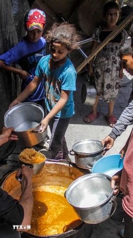 Các em nhỏ nhận thực phẩm cứu trợ tại Jabalia, Dải Gaza. (Ảnh: THX/TTXVN)