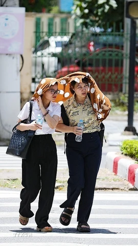 Hai người phụ nữ che chắn nắng khi băng qua đường. (Ảnh: Trọng Đạt/TTXVN)