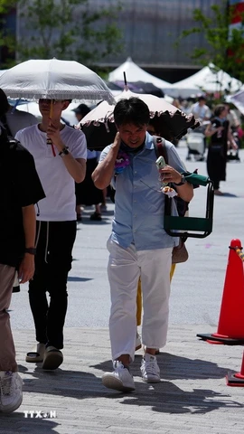 Người dân di chuyển trên đường phố dưới trời nắng nóng tại Osaka, Nhật Bản. (Ảnh: THX/TTXVN)