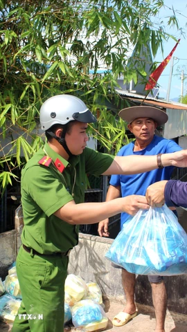 Lực lượng tại chỗ phối hợp với các nhóm thiện nguyện phân phối thức ăn cho các người dân vùng ngập Hàm Thắng. (Ảnh: Hồng Hiếu/TTXVN)
