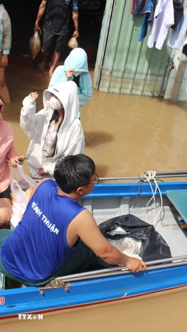 Các nhóm thiện nguyện dùng xuồng chèo đến phát cơm tận tay người dân vùng ngập nghiêm trọng. (Ảnh: Hồng Hiếu/TTXVN)