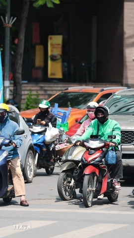 Khẩu trang, áo chống nắng là những thứ không thể thiếu cảu người dân ở Hà Nội khi tham gia giao thông trong những ngày nắng nóng. (Ảnh: Lê Đông/TTXVN)