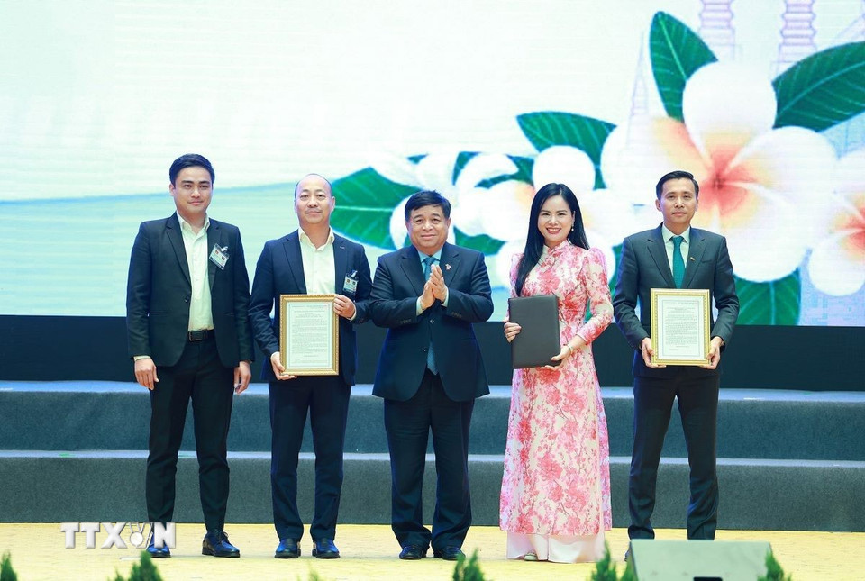 Bộ trưởng Bộ Kế hoạch và Đầu tư Nguyễn Chí Dũng trao chứng nhận đăng ký và thoả thuận đầu tư cho các doanh nghiệp Việt Nam có hợp tác với Lào. (Ảnh: Dương Giang/TTXVN)