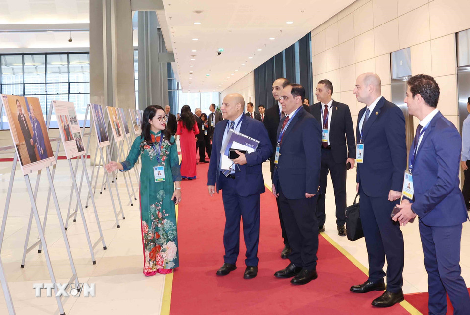 Đại biểu quốc tế tham quan trưng bày ảnh của Thông tấn xã Việt Nam tại Lễ mở ký Công ước Hà Nội, sáng 25/10. (Ảnh: Phương Hoa/TTXVN)