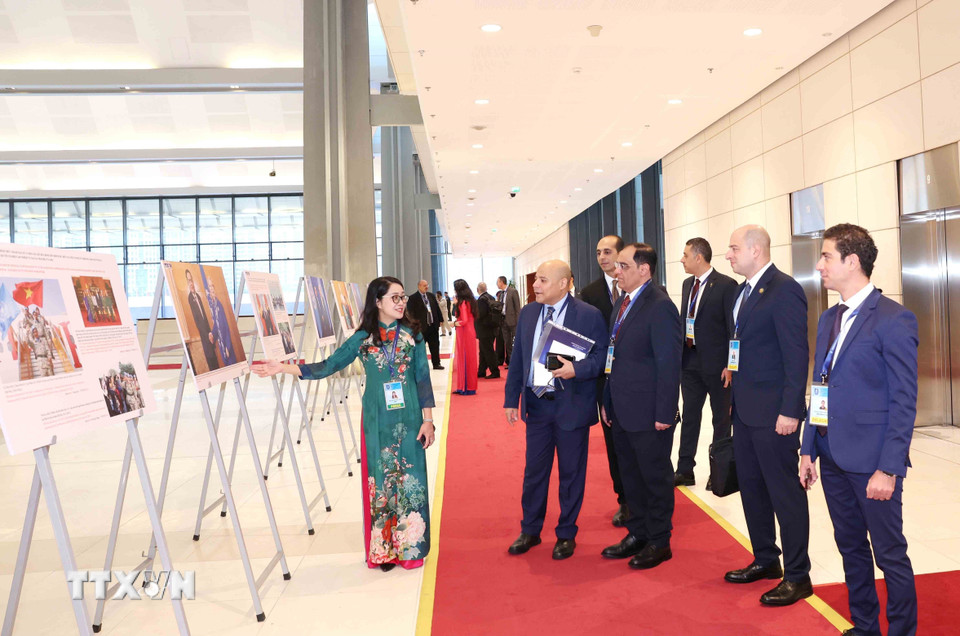 Đại biểu quốc tế tham quan trưng bày ảnh của Thông tấn xã Việt Nam tại Lễ mở ký Công ước Hà Nội, sáng 25/10. (Ảnh: Phương Hoa/TTXVN)