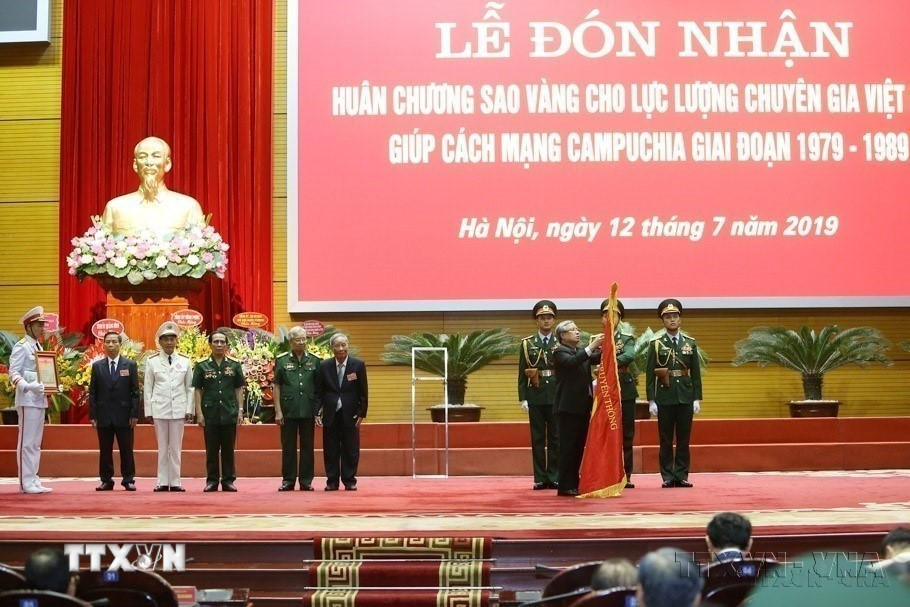 Thường trực Ban Bí thư Trần Quốc Vượng gắn Huân chương Sao vàng của Chủ tịch nước lên Cờ truyền thống của Lực lượng chuyên gia Việt Nam giúp Cách mạng Campuchia. (Ảnh: Dương Giang/TTXVN)