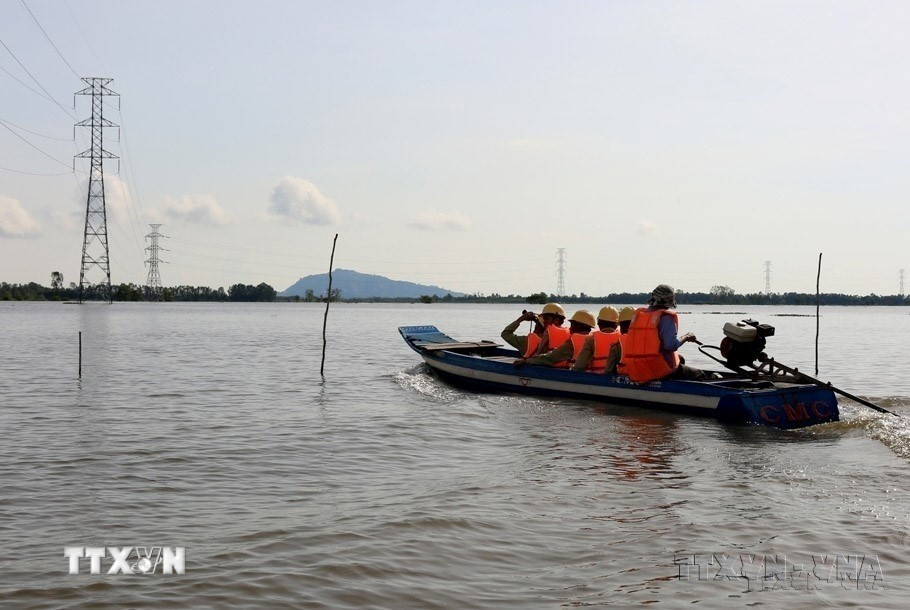 Công nhân Công ty Truyền tải Điện 4 (Tập đoàn Điện lực Việt Nam) kiểm tra an toàn đường dây 220kV Châu Đốc-Takeo trong mùa lũ, đảm bảo điện cung cấp cho Campuchia. (Ảnh: Ngọc Hà/TTXVN)