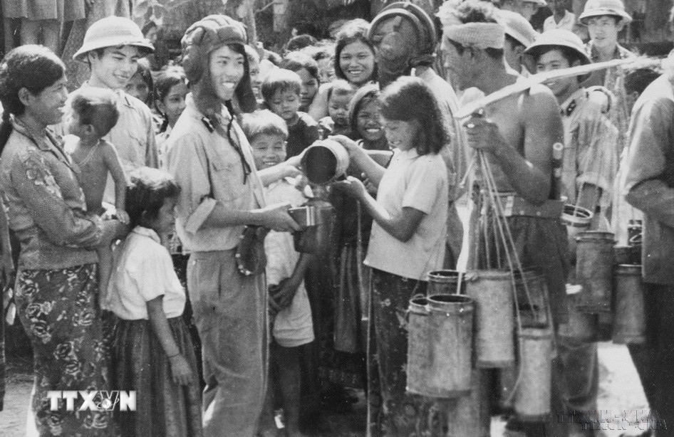 Người dân Campuchia mang nước thốt nốt đến cho bộ đội tình nguyện Việt Nam trong những ngày giúp dân Campuchia thu hoạch lúa. Hình ảnh thắm đượm tình nghĩa quân dân Việt Nam - Campuchia trong cuộc chiến đấu lật đổ chế độ diệt chủng Pol Pot. (Ảnh: TTXVN)