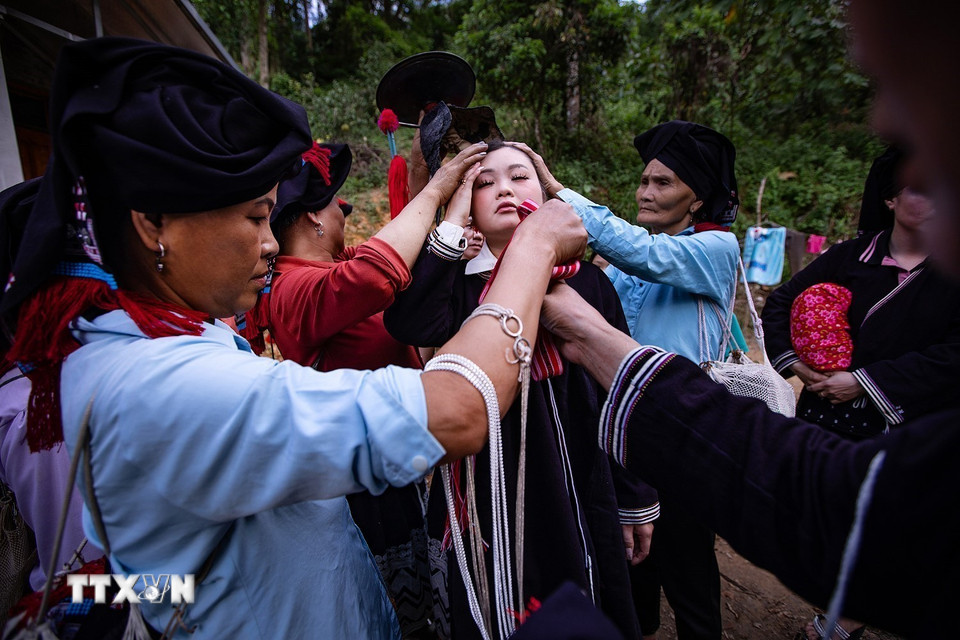 Cô dâu được các bà, cô, chị trong họ mặc cho nhiều lớp váy áo truyền thống. (Ảnh: Trọng Đạt/TTXVN)