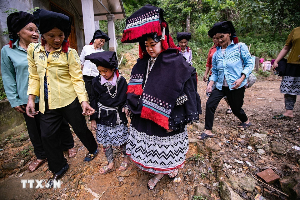 Trong đoàn rước, cô gái nhỏ dẫn dâu cầm tay cô dâu đi giữa các bà mối cảm ơn họ hàng hai bên. (Ảnh: Trọng Đạt/TTXVN)