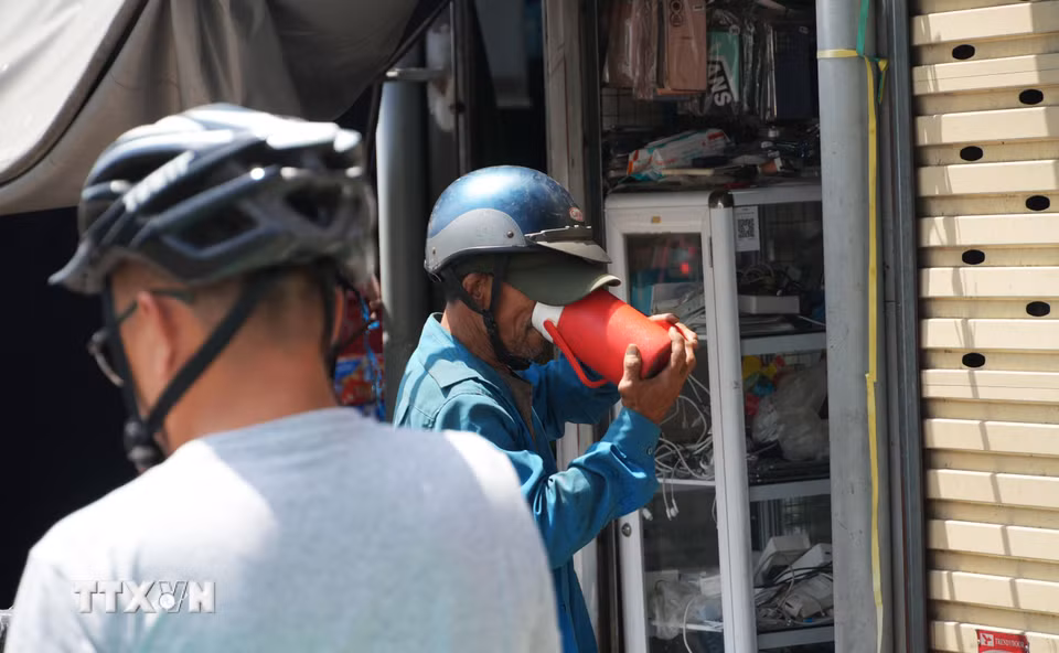 Tiếp nước cho cơ thể khi làm việc ngoài trời nắng nóng gay gắt ở chợ Đông Ba, phường Phú Xuân, thành phố Huế. (Ảnh: Nguyên Lý/TTXVN)