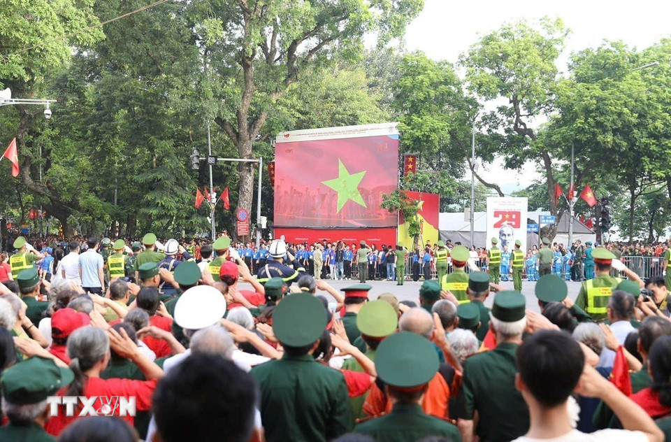 Người dân thực hiện nghi lễ chào cờ tại khu vực hồ Hoàn Kiếm. (Ảnh: Phan Phương/TTXVN)