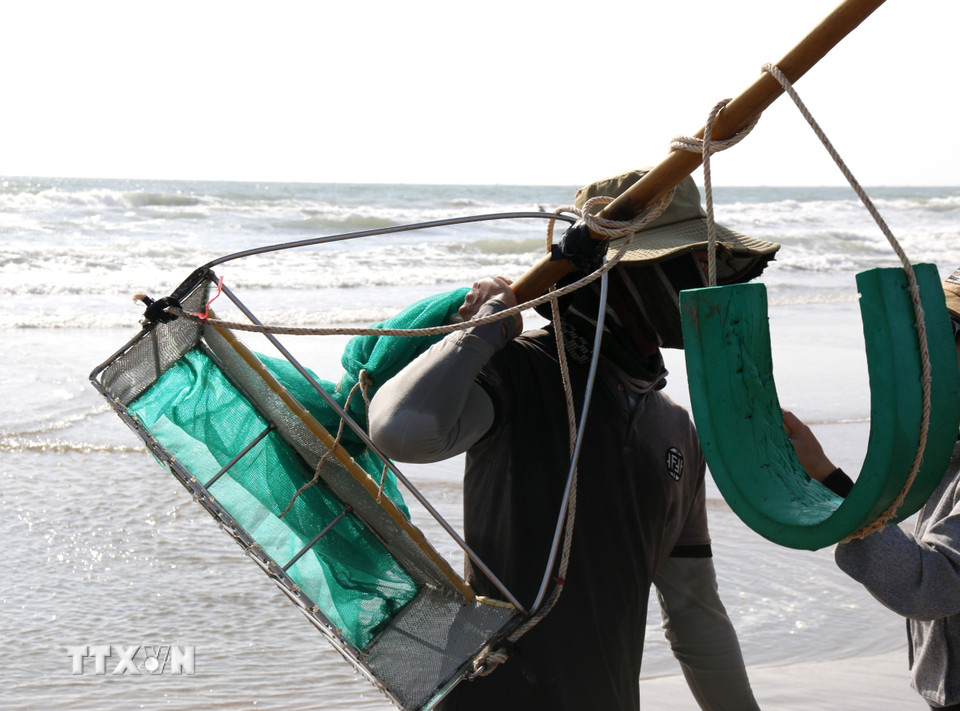 Dụng cụ cào chằng chằng khá đơn giản, gồm một cái cào làm bằng inox, sau họng cào gắn bao lưới dài khoảng 3 mét. (Ảnh: Hồng Hiếu/TTXVN)