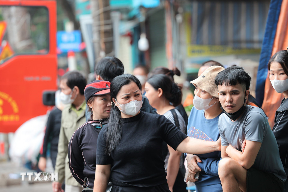 Nhiều tiểu thương động viên nhau giữa khung cảnh ngổn ngang sau vụ cháy chợ Xanh Định Công, phường Phương Liệt, Hà Nội. (Ảnh: Lê Đông/TTXVN)