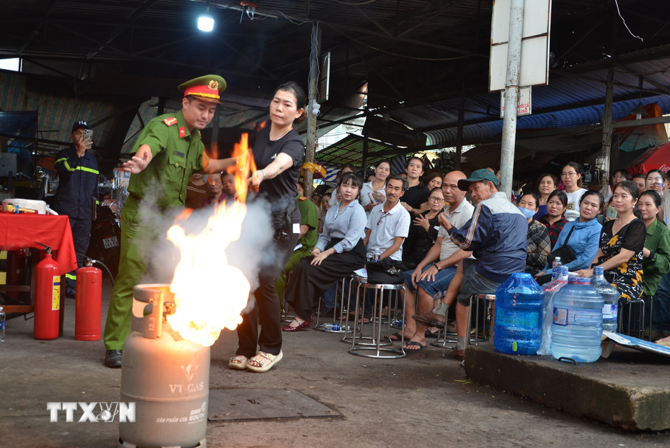 Cán bộ Phòng Cảnh sát phòng cháy chữa cháy và cứu nạn, cứu hộ, Công an Thành phố Hồ Chí Minh hướng dẫn các tiểu thương cách chữa cháy khi có sự cố xảy ra. (Ảnh: Linh Sơn/TTXVN)