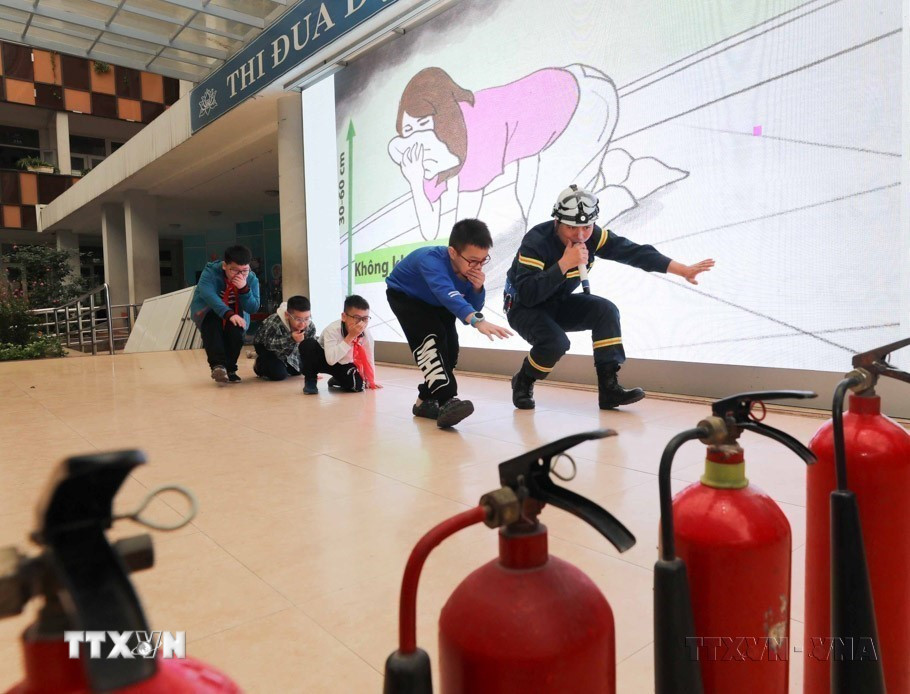 Cán bộ cảnh sát phòng cháy chữa cháy hướng dẫn học sinh trường Tiểu học Ngọc Khánh (quận Ba Đình) cách di chuyển thoát hiểm khi xảy ra cháy. (Ảnh: Thanh Tùng/TTXVN)