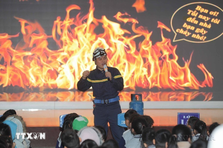 Cán bộ phòng cháy chữa cháy tuyên truyền, hướng dẫn học sinh trường tiểu Ngọc Khánh (quận Ba Đình) nhận biết các dấu hiệu của đám cháy, nguy cơ gây tai nạn, nhận biết các tín hiệu báo động cháy và kỹ năng thoát nạn trong đám cháy, cách chọn lối thoát, cách sử dụng thiết bị bảo vệ cơ quan hô hấp và cơ thể khi có xảy ra cháy, nổ. (Ảnh: Thanh Tùng/TTXVN)