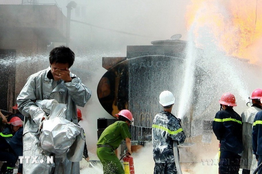 Một chiến sỹ phòng cháy chữa cháy bị lửa táp vào mặt đi ra, trong khi các chiến sỹ khác vẫn tích cực dập đám cháy trong vụ cháy lớn tại cây xăng số 2B Trần Hưng Đạo (Hà Nội). (Ảnh: Doãn Tấn/TTXVN)