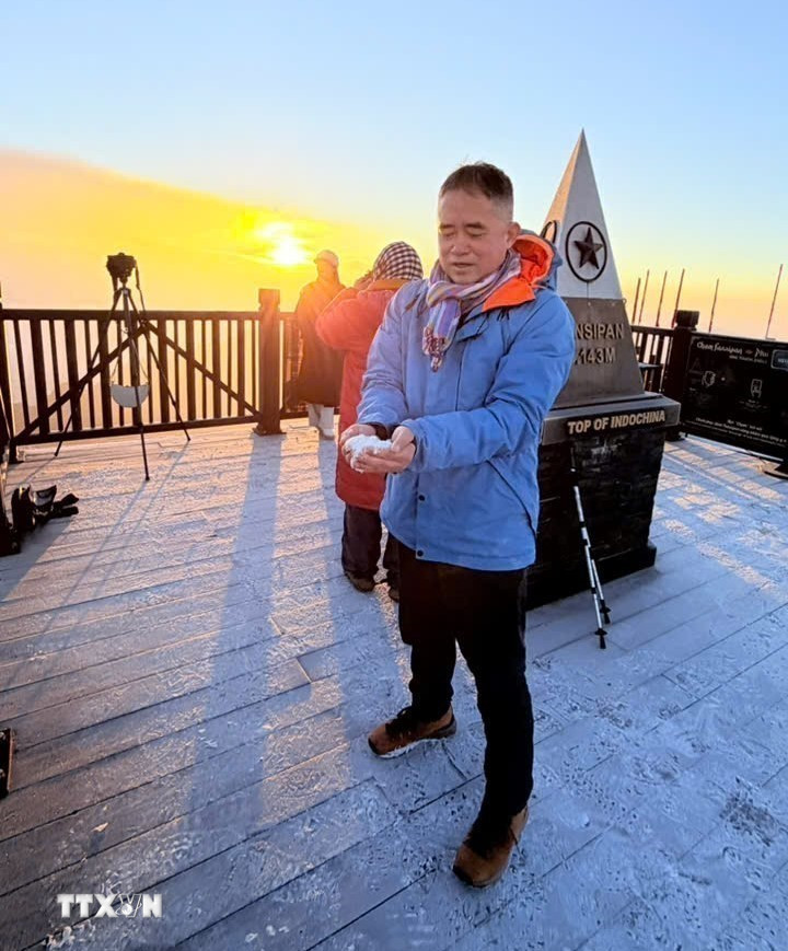 Du khách thích thú khi được trải nghiệm băng giá trên đỉnh Fansipan. (Ảnh: TTXVN phát)