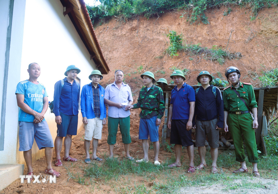 Ông Lương Tuấn Dũng, Phó Chủ tịch Ủy ban Nhân dân xã Nga My cùng các thành viên trong tổ công tác trao kinh phí hỗ trợ cho gia đình có nhà bị sạt lở. (Ảnh: Xuân Tiến/TTXVN)