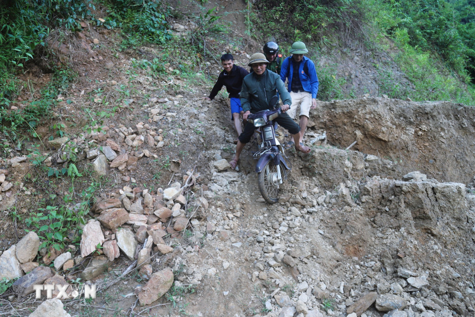 Lực lượng chức năng trong hành trình vượt qua các điểm sạt lở, sụt lún để đến bản Na Ngân bị cô lập. (Ảnh: Xuân Tiến/TTXVN)