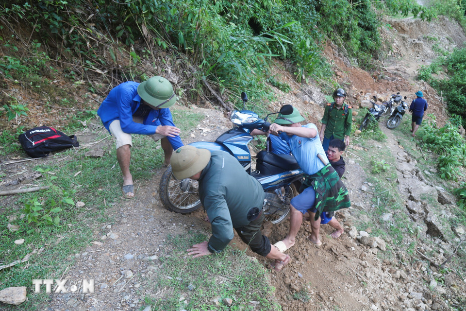 Lực lượng chức năng trong hành trình vượt qua các điểm mặt đường bị đứt gãy, sụt trượt xuống sâu hơn 2m để đến bản Na Ngân bị cô lập. (Ảnh: Xuân Tiến/TTXVN)