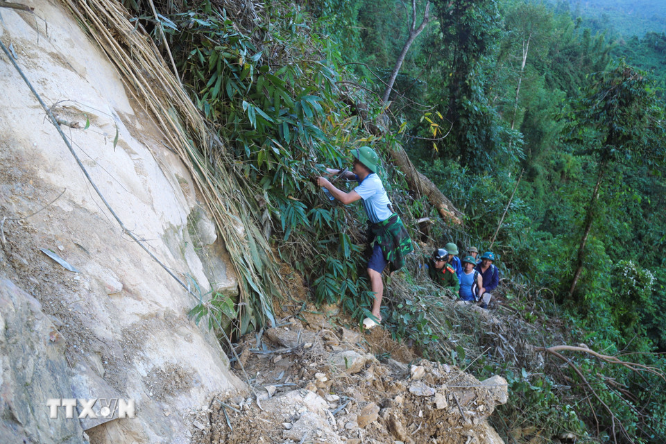 Tại những điểm sạt lở núi, ta-luy dương nghiêm trọng trên đường vào bản Na Ngân, lực lượng chức năng phải bám cây rừng bên vách vực cheo leo để di chuyển. (Ảnh: Xuân Tiến/TTXVN)