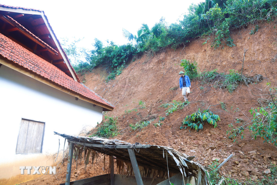 Thành viên trong tổ công tác của Ủy ban Nhân dân xã Nga My kiểm tra tại điểm sạt lở vách ta-luy dương khiến hàng chục khối đất, đá và cây rừng tràn xuống nhà dân. (Ảnh: Xuân Tiến/TTXVN)
